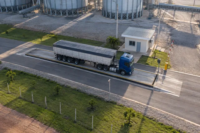 Vista de uma balança rodoviária com caminhão e equipamentos de pátio